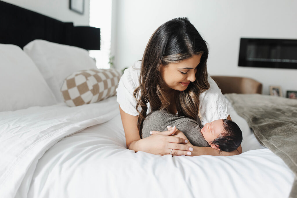McKinney newborn photographer capturing mother holding newborn baby in soft natural window light